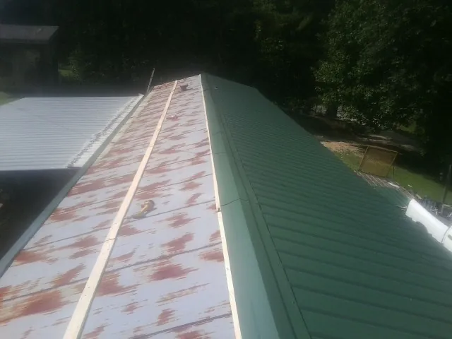 Old rusted panels beside newly installed green metal roofing — Wind Damage Roof Repair by Roofing Brothers in Palm Beach Gardens