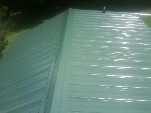 New green metal panels meeting at the ridge of a roof — Flat Roof Repair work by our crew in Palm Beach Gardens