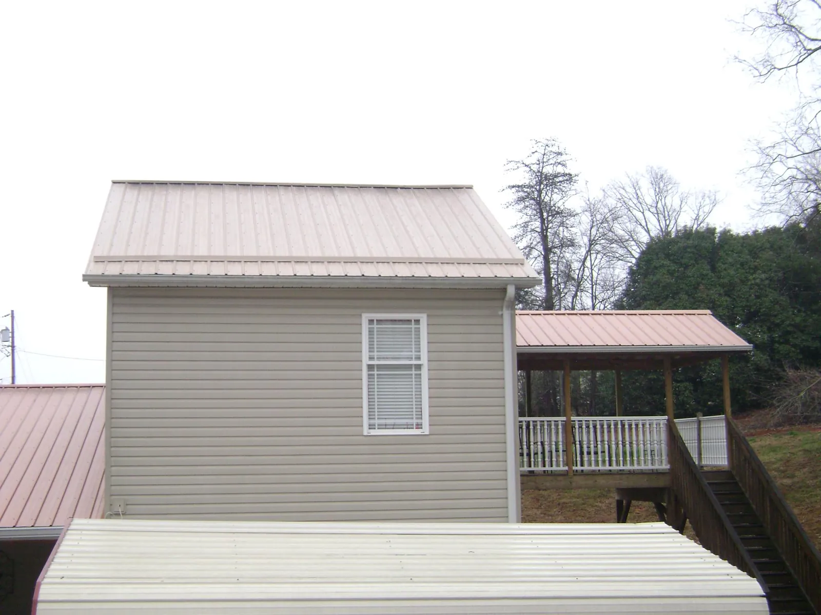 Tan metal roofs on a two story addition and attached porch, from a Roof Replacement job in Palm Beach Gardens